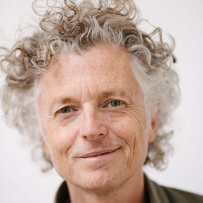 Headshot of Billy: a tall, slim, white man in his fifties with curly hair.