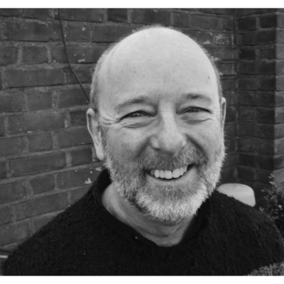 Headshot of Willie, a white man in his fourties with a bright smile and a grey-white beard and a shaved head.