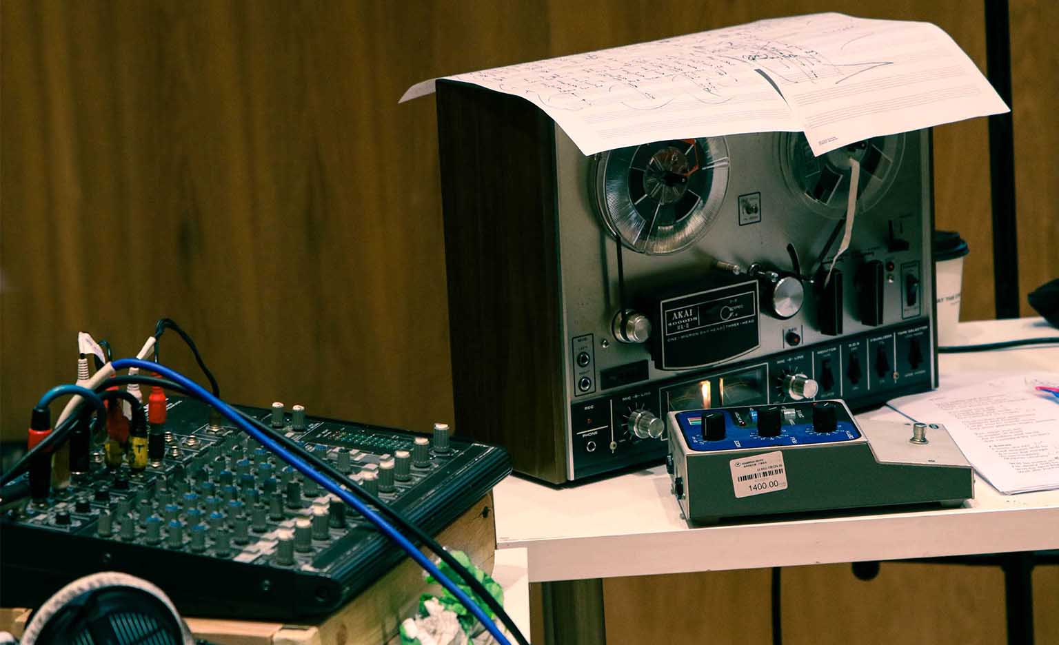 Different parts of recording equipment on a table, alongside some music sheet.