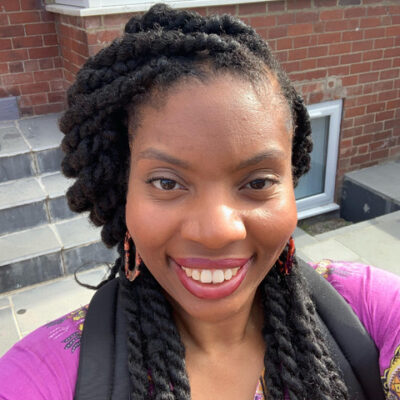 Black woman wearing a purple parka with black scarf. She is smiling up at the camera.