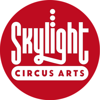 Skylight Circus Arts logo: a red circle with quirky white writing that reads: "Skylight Circus Arts".